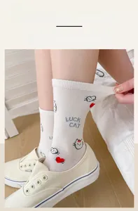 Close-up of elastic white crew socks featuring cartoon cat and heart print patterns