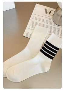 Detail of cream rib-knit mid-calf socks with black stripe pattern on cotton texture
