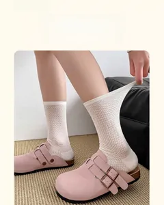 Detailed view of white mesh crew socks with breathable cotton fabric and pink suede clogs