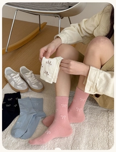Close-up of ribbed knit socks featuring delicate bow jacquard patterns in multiple colors