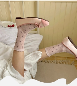 Detail of pink floral crew socks with ruffle cuffs paired with ballet flat shoes