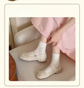 Close-up of white crew socks with butterfly embroidery and beaded flower shoes