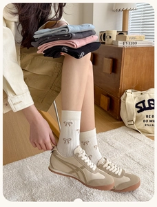 Detailed view of combed cotton socks featuring exquisite bow embroidery and soft pastel colors