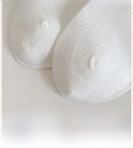 Macro shot of white knitted socks showing seamless toe stitch and vertical ribbed texture