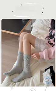 Detail of gray mid-calf socks with plaid bows shown on model in home setting