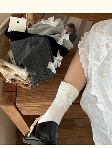 Dettaglio di calze grigie con fiocchi in pizzo bianco e trama a nido d'ape a maglia