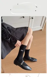 Close-up of black ribbed crew socks featuring delicate white bow embroidery and elastic cuffs