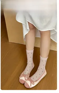 Close-up of pink crew socks with floral patterns and ruffled edges on wooden floor