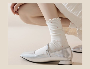 Close-up of silver Mary Jane shoes with pink polka dot socks and wavy frill edges