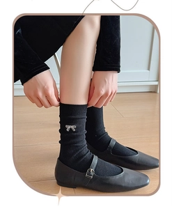 Detail of delicate white bow embroidery on black ribbed cotton crew socks for women