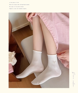 Detail of white cotton blend mid-calf socks with ruffle trim and butterfly embroidery