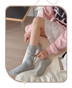 Detail of light gray Lolita socks with sweet plaid bows in a cozy bedroom setting