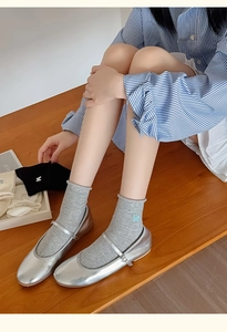 Detail of grey crew socks featuring delicate bow embroidery and stylish rolled cuffs