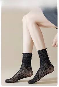 Detail of black hollow lace socks with floral patterns and ruffled agaric edges