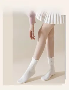 Close-up of white crew socks with pink polka dots and ruffled hem details