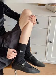 Detail of black ribbed socks with white bow embroidery paired with Mary Jane shoes