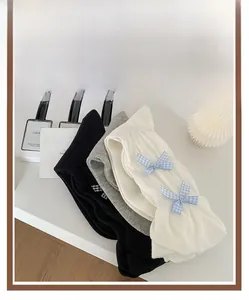 Detail of sweet mid-calf socks with blue checkered bows in black, grey and white