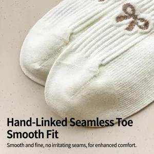 White cotton knit mid-calf socks with brown bow pattern and seamless toe detail