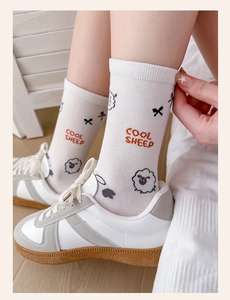 Detail of white cotton sock with cartoon sheep design and cool sheep text worn with sneakers