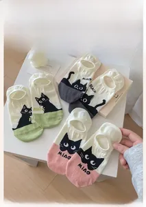 Flat lay of pink, green and grey invisible boat socks with cute cartoon black cat patterns