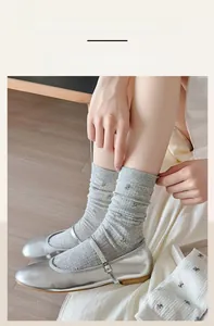 Close-up of light grey floral embroidery socks with high elastic cuffs and ribbed texture