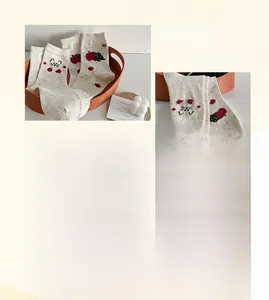 Close-up of beige crew socks featuring cute black cat and red apple embroidery details