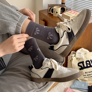 Mid-calf cotton socks with bow jacquard pattern paired with vintage casual sneakers