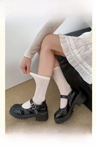 Detail of white lace crew socks with bow pattern paired with black platform Mary Janes