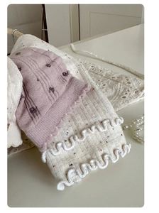 Close-up of floral knit socks and cream lace ruffled trim with pearl decorations