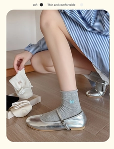 Detail of light gray crew socks featuring delicate blue butterfly embroidery on soft fabric