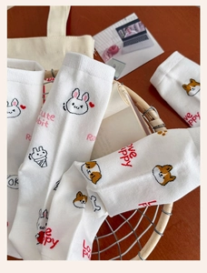 Close-up of white cotton socks with cute cartoon rabbit and puppy patterns in a basket