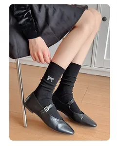 Detail of black crew socks with white bow embroidery paired with Mary Jane flat shoes