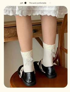 Dettaglio di calze in pizzo crema con fiocchi e scarpe Mary Jane nere eleganti