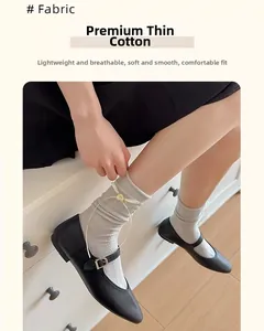 Dettaglio di calzini in cotone grigio chiaro con fiocchi di nastro bianco e fiori