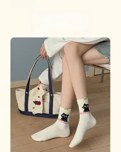 Close-up of cute black cat pattern and green 3D detail on beige mid-calf cotton socks