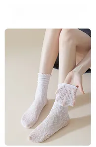 Detailed view of white floral lace mid-calf socks with delicate ruffled edges for women