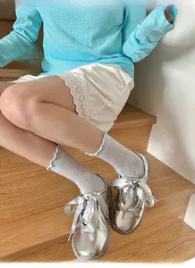 Close-up of white mesh socks with floral embroidery and satin bow silver shoes