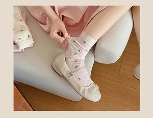 Close-up of floral mesh socks with delicate knit texture and pearl Mary Jane shoes
