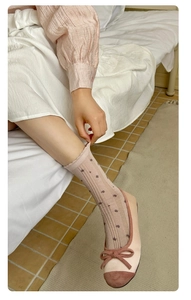 Close-up of floral lace crew socks paired with pink bow ballet flats in a cozy setting