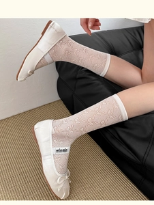 Detailed macro of white mesh mid-calf socks with floral lace and bow patterns