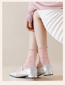 Detail of pink polka dot crew socks with ruffled cuffs and silver Mary Jane shoes