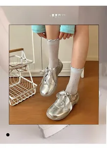 Detail of white crew socks featuring hollow bow jacquard and frill edge with silver shoes