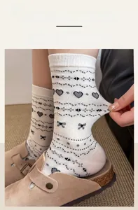 Close-up of white crew socks with grey bow patterns showing elastic cuff stretch