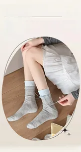 Detailed view of grey knit socks with blue ribbon bows and delicate rolled edges