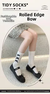 Close-up of white calf socks with three black bows and delicate rolled edge detail