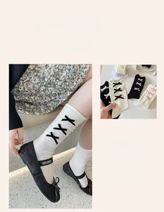 Close-up of white calf socks featuring black lace-up bows and ballet flats detail