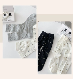 Detail of floral embroidery on ribbed cotton mid-calf socks in grey, white and black