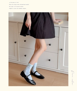 Calze azzurre con fiocco in raso bianco abbinate a scarpe Mary Jane nere stile collegiale