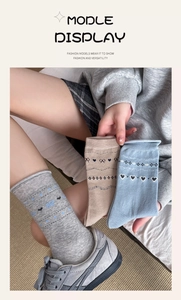 Close-up of three pairs of vintage heart and bow pattern knit socks in soft pastel tones