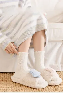 Close-up of white plush bow socks with knitted texture and matching starry slippers